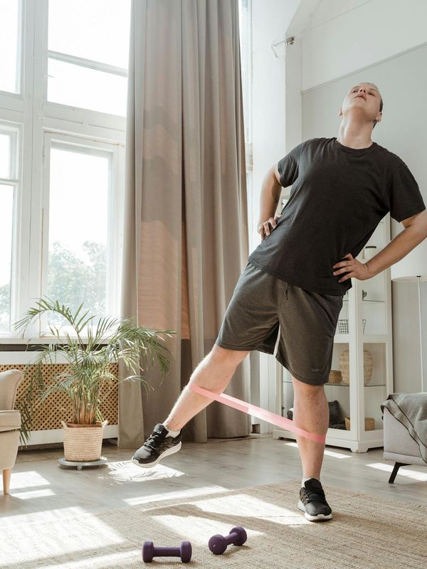 A person performing a stretching exercise in a minimalist room with natural light.